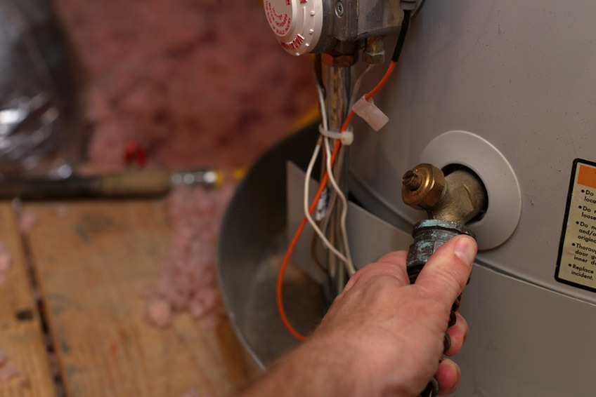 Hand attaches hose to water heater drain